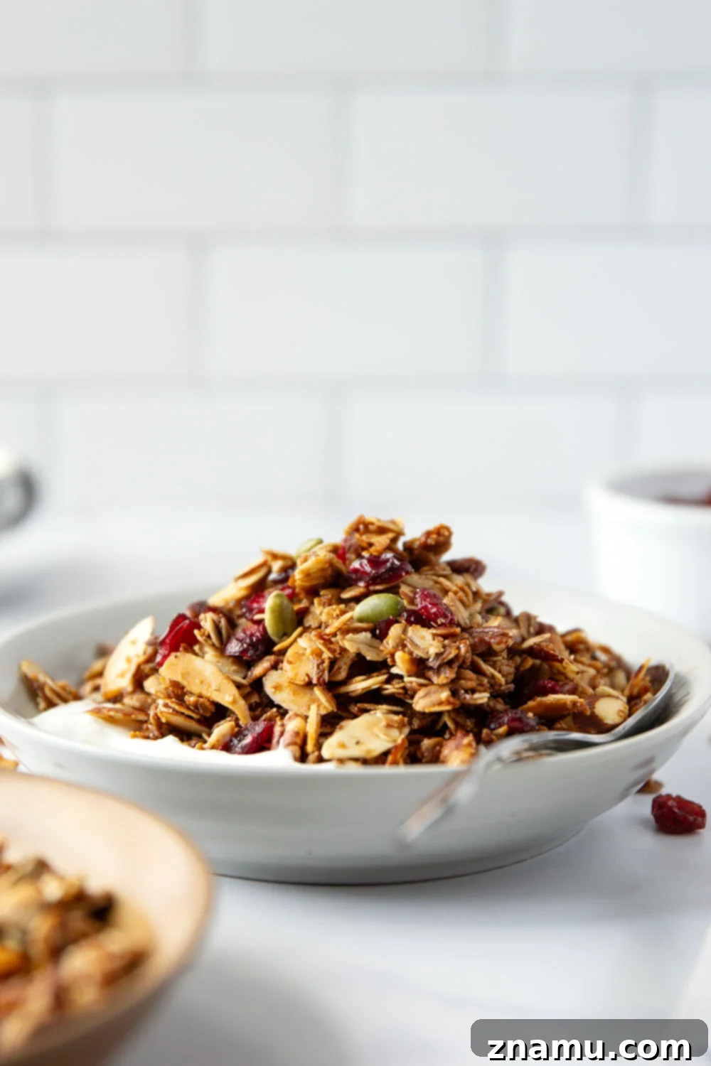 Sweet Maple Crunch 2 Crunchy maple granola with nuts and dried cranberries on a baking sheet, ready to be served for a healthy breakfast.