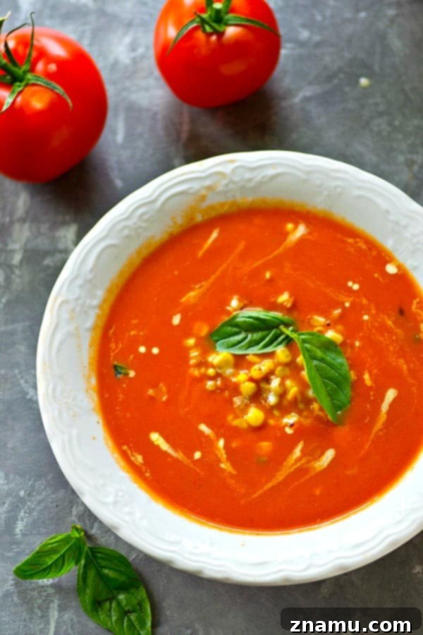 Sun-Kissed Tomato-Basil Soup with Charred Sweet Corn 4 Whole tomatoes and garlic cloves roasting on a baking sheet, drizzled with olive oil.