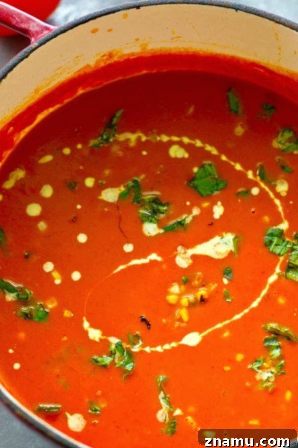 Sun-Kissed Tomato-Basil Soup with Charred Sweet Corn 5 Rich, creamy basil roasted tomato soup served in a bowl, garnished with fresh basil.