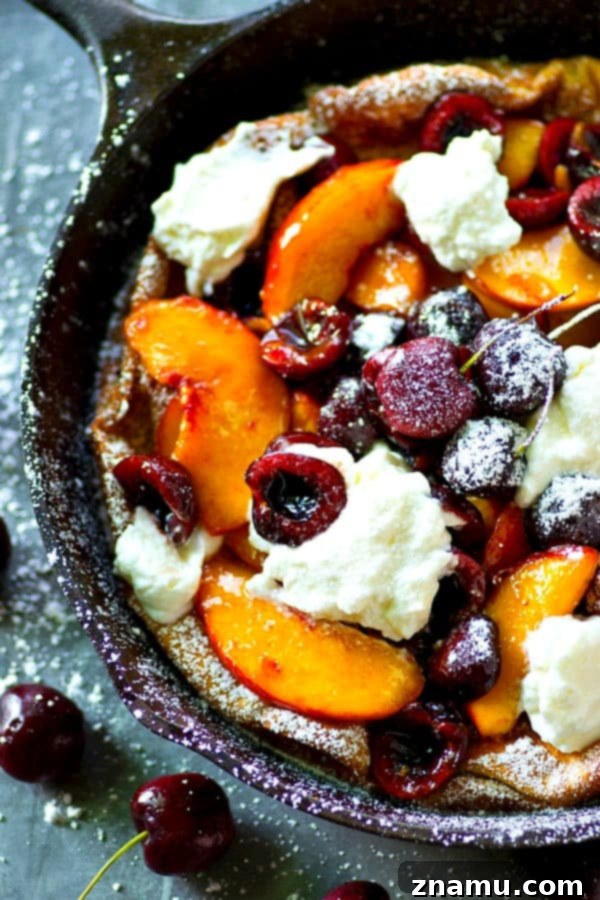 Fluffy honey whipped cream and juicy summer cherries and peaches are piled high into this summery cherry peach dutch baby that's ready in 30 minutes flat!