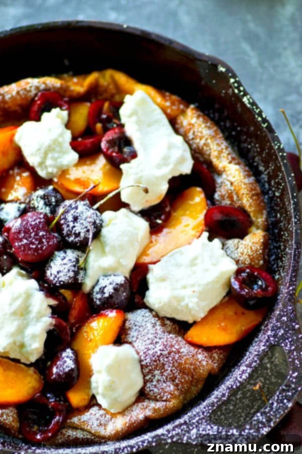 Fluffy honey whipped cream and juicy summer cherries and peaches are piled high into this summery cherry peach dutch baby that's ready in 30 minutes flat!