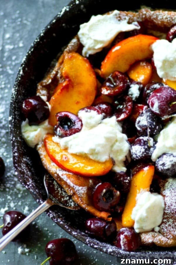 Fluffy honey whipped cream and juicy summer cherries and peaches are piled high into this summery cherry peach dutch baby that's ready in 30 minutes flat!