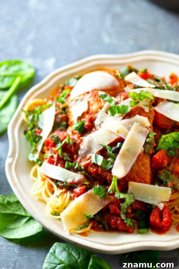 Tuscan Braised Chicken with Spinach and Tomato 5 A fork taking a bite of Italian Braised Chicken with pasta