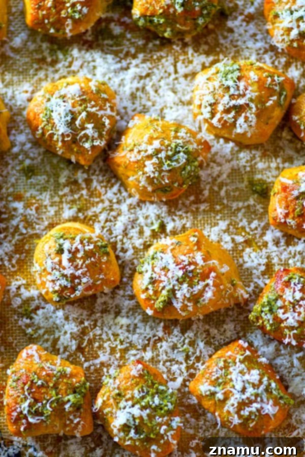Pillowy Pesto Parmesan Pretzel Bites 4 Hand reaching for a Parmesan Pesto Soft Pretzel Bite, showcasing its delicious topping