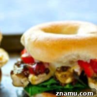 A plated Roasted Red Pepper Pesto Chicken Bagel Sandwich, showing the crispy toasted bagel with a rich filling of chicken, pesto, roasted red peppers, and melted cheese.