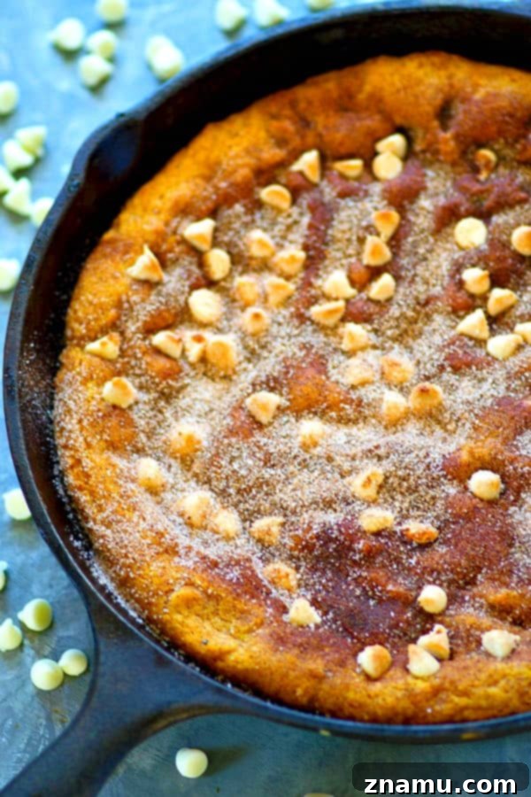 Pumpkin & White Chocolate Snickerdoodle Skillet 3 Close-up of a perfectly baked white chocolate pumpkin snickerdoodle skillet cookie, showcasing its soft interior and cinnamon-sugar topping.