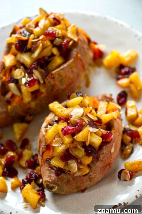 Harvest Stuffed Cranberry Apple Sweet Potatoes 4 An aerial view of prepared twice-baked sweet potatoes on a rustic wooden surface, highlighting the vibrant colors of the filling.