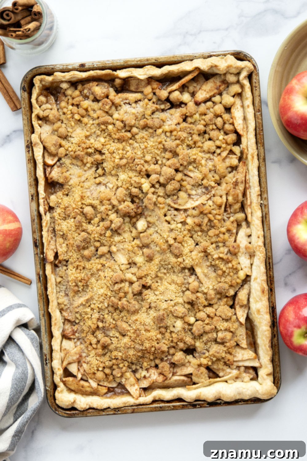 Close-up of a golden brown apple slab pie, showcasing the crumbly streusel topping and bubbling apple filling.