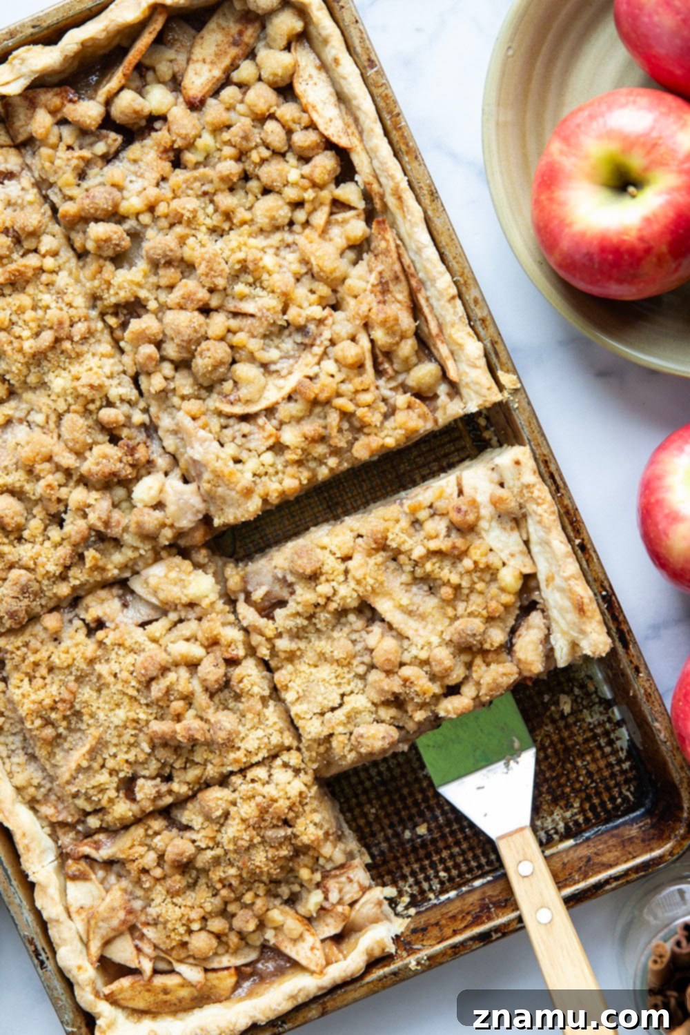 A slice of apple slab pie on a plate, showing the layers of crust, apple filling, and streusel topping.