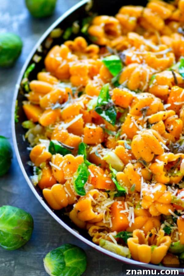 Shaved Brussels Sprouts and Delicata Squash Zucchette Pasta 5 An enticing view of the finished Zucchette pasta skillet, showcasing the golden-brown vegetables, the unique pasta shape, and a generous sprinkle of fresh Parmesan.