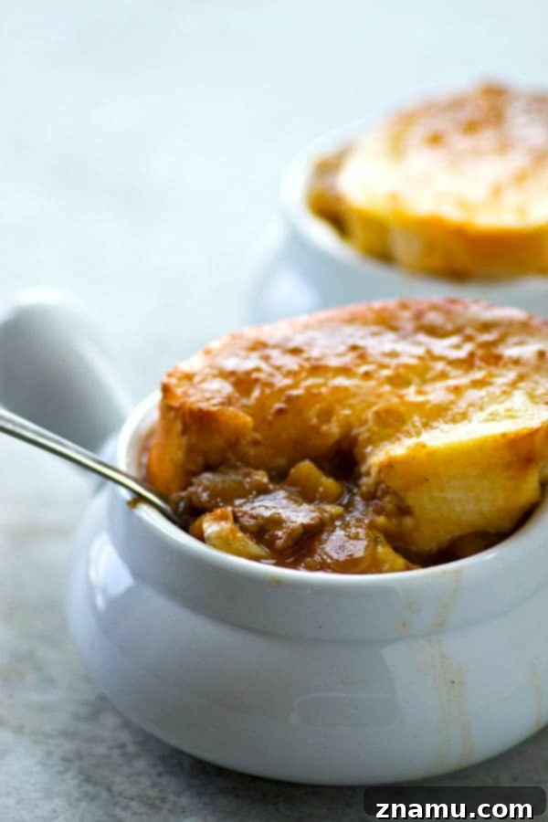 A delicious bowl of Steak Potato French Onion Soup, richly colored and topped with melted Swiss cheese and a golden-brown crouton.