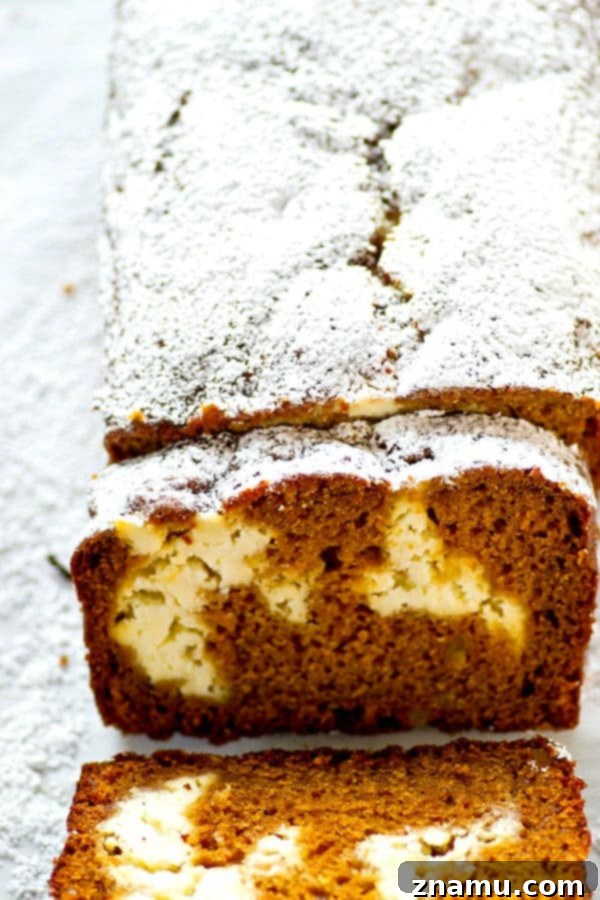 Marbled Gingerbread Cheesecake Bread 3 Close-up of a slice of Gingerbread Cheesecake Swirl Quick Bread, revealing the distinct layers of moist gingerbread and the smooth, white cheesecake ribbon. The comforting aroma of spices seems to emanate from the image.