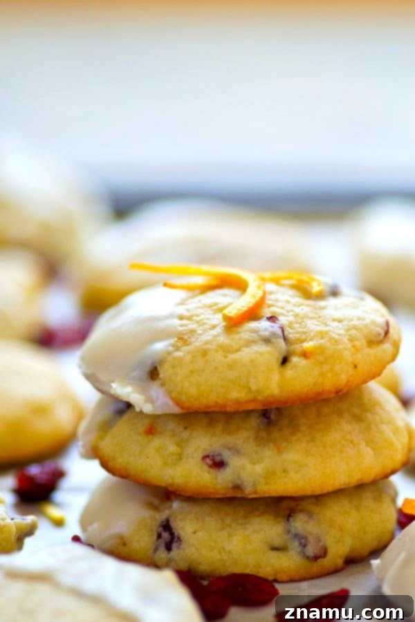 Several festive white chocolate cranberry orange sugar cookies stacked on a plate, showcasing their inviting appearance and generous white chocolate coating.