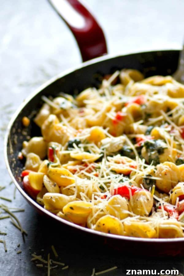 A bowl of the finished orechiette pasta, garnished with fresh herbs and Parmesan, ready to be enjoyed.