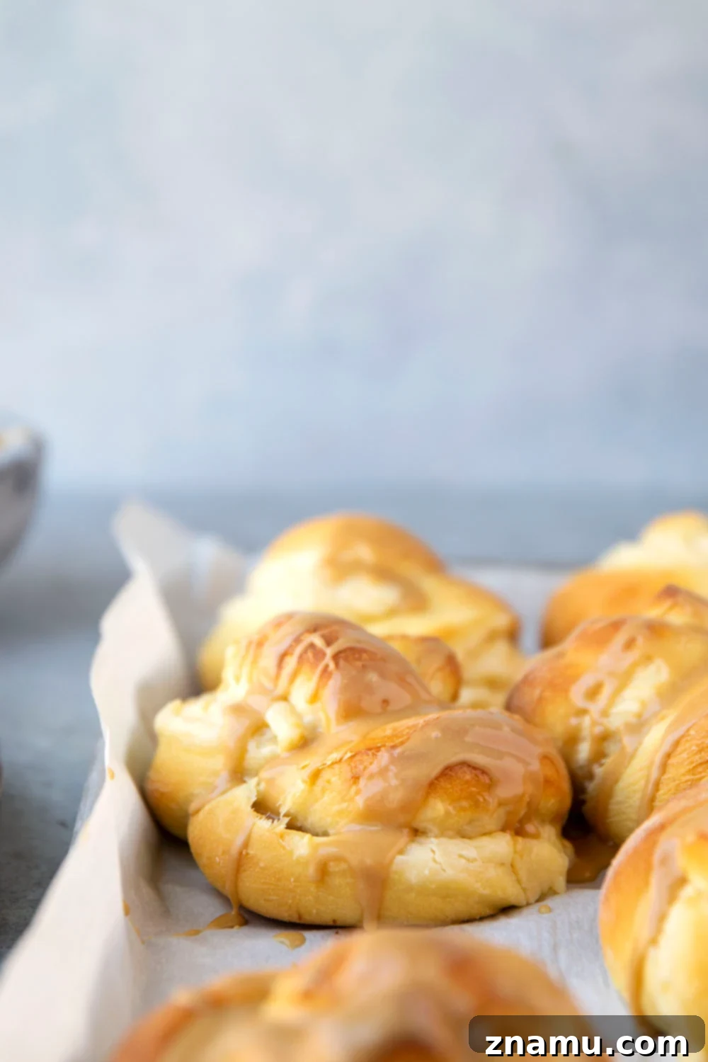 Decadent Cream Cheese Morning Buns with Coffee Glaze 6 Unbaked cream cheese morning buns, perfectly shaped into knots and arranged on a baking sheet, ready for their final rise.