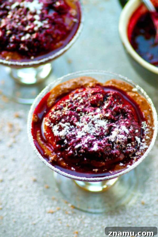Decadent Chocolate Mousse with Wine-Infused Raspberries 5 Two elegant glasses of dark chocolate mousse with red wine raspberry sauce, garnished with powdered sugar and chocolate shavings.