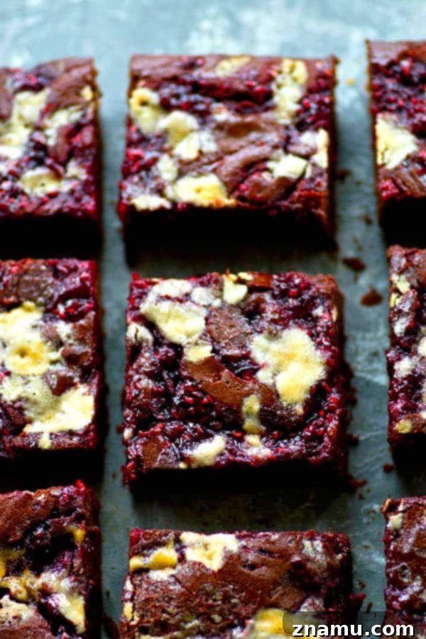 White Chocolate Raspberry Marbled Brownies 3 Close-up of a square of raspberry jam swirled brownie with white chocolate chunks, showing its incredibly fudgy texture