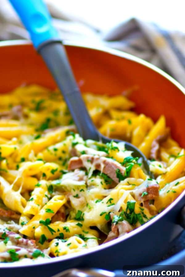 Single-Skillet Philly Cheesesteak Penne 4 Overhead view of One-Pot Philly Cheesesteak Penne Pasta in a black skillet with a wooden spoon