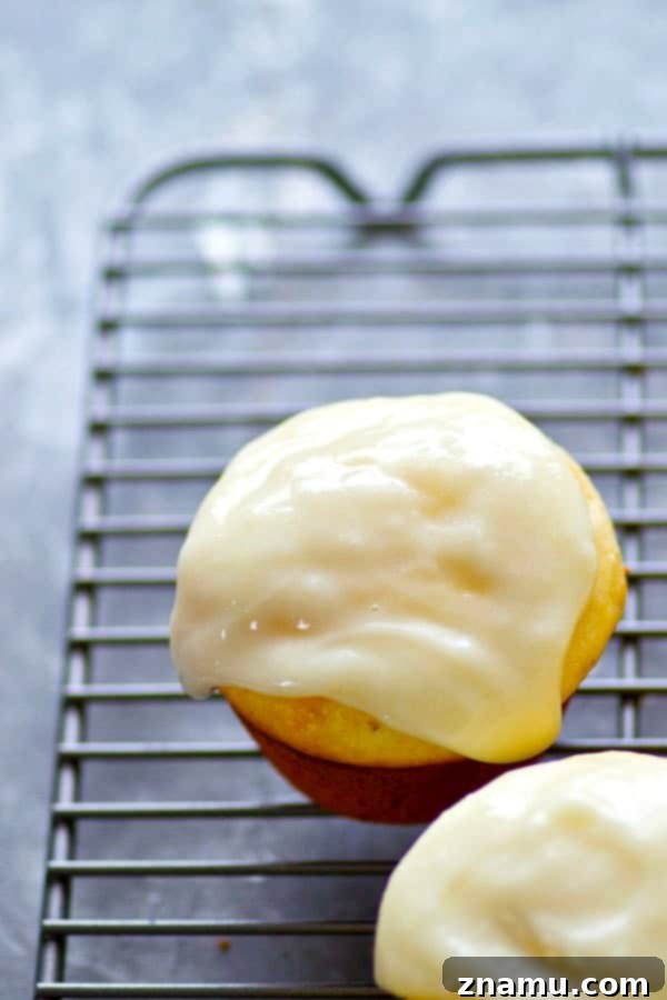 Sunshine-Glazed Meyer Lemon Cream Cheese Muffins 3 Close-up of Meyer lemon cream cheese muffins cooling on a rack, with a vibrant yellow hue.