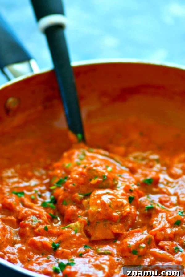 Homestyle Paprikash with Buttery Garlic Noodles 3 Close-up of creamy chicken paprikash with tender chicken pieces, vibrant red sauce, and fresh parsley, perfect for a cozy dinner.