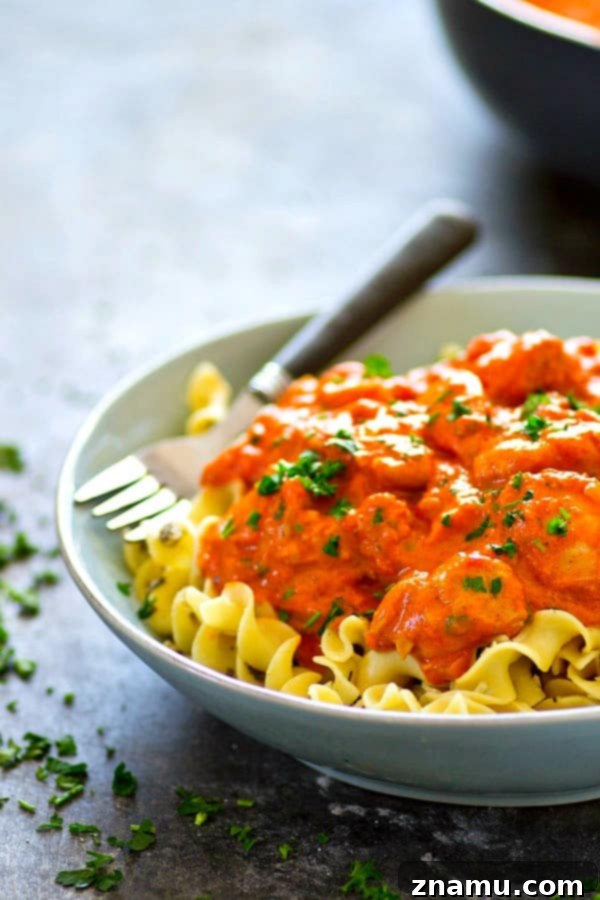 Homestyle Paprikash with Buttery Garlic Noodles 4 A generous serving of chicken paprikash topped with fresh parsley, alongside a forkful of garlic butter noodles, ready to be enjoyed.