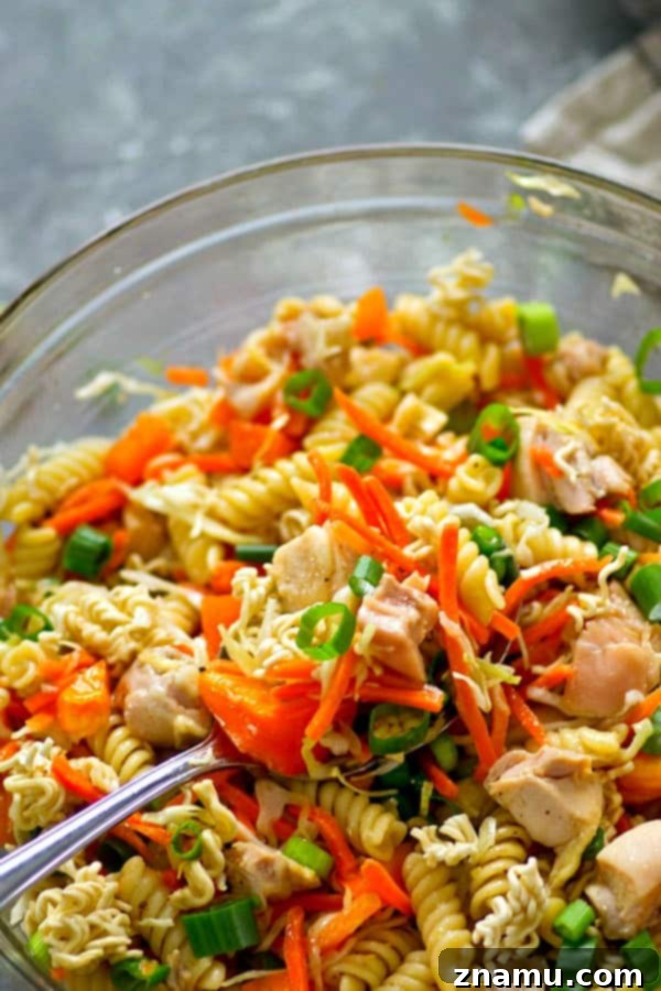 A large bowl of Asian Chicken Crunch Pasta Salad ready to be served, showcasing colorful ingredients