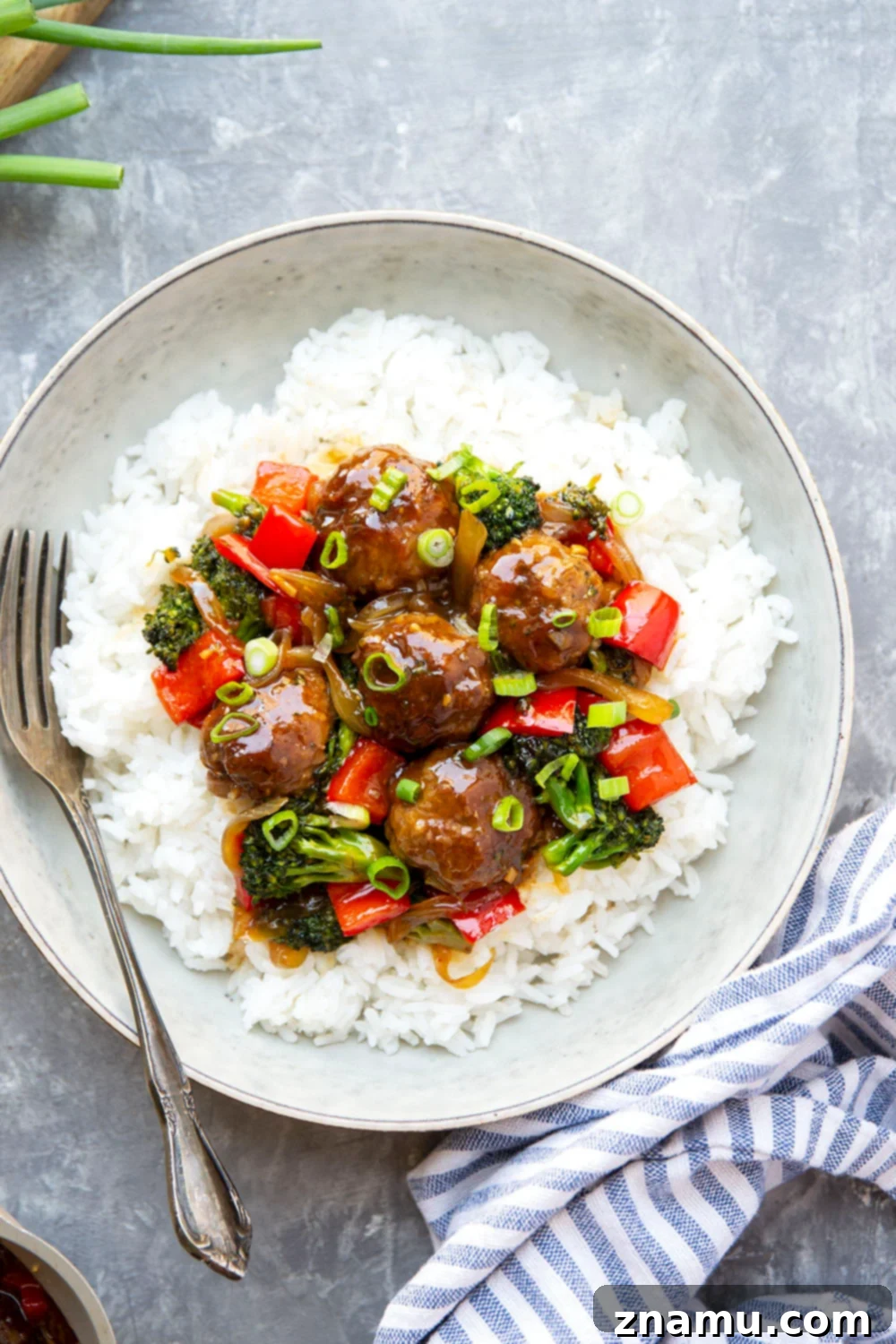 Mongolian Glazed Beef Bites 6 A serving of Mongolian Beef Meatballs with rice and green onions, ready to eat.