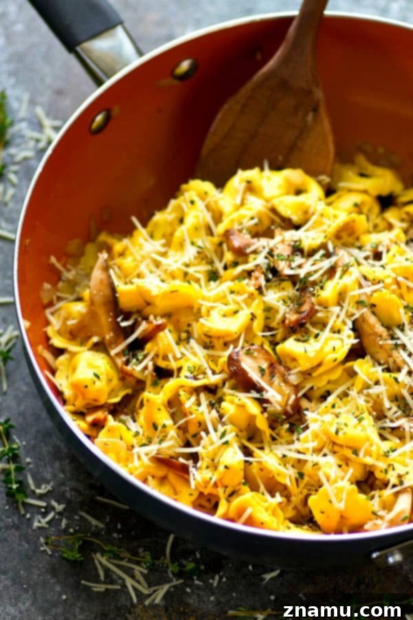 Close-up of creamy garlic butter Asiago tortellini with shiitake mushrooms in a skillet.