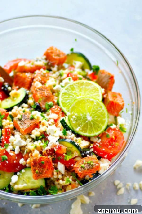 Close-up of a vibrant Greek Seared Salmon Couscous Salad, showcasing tender salmon pieces, colorful vegetables, and pearl couscous