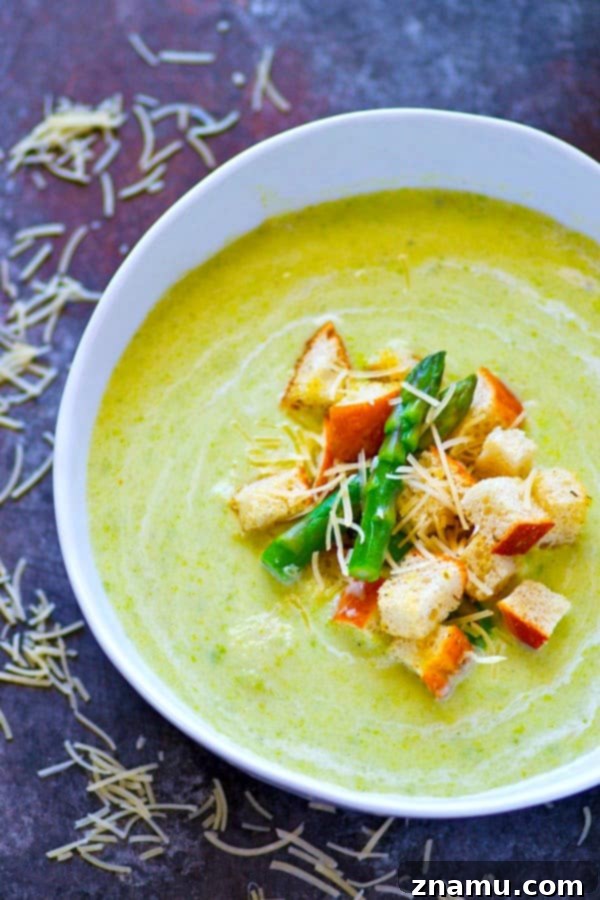 Vibrant green cream of asparagus soup in a bowl with crispy Parmesan croutons