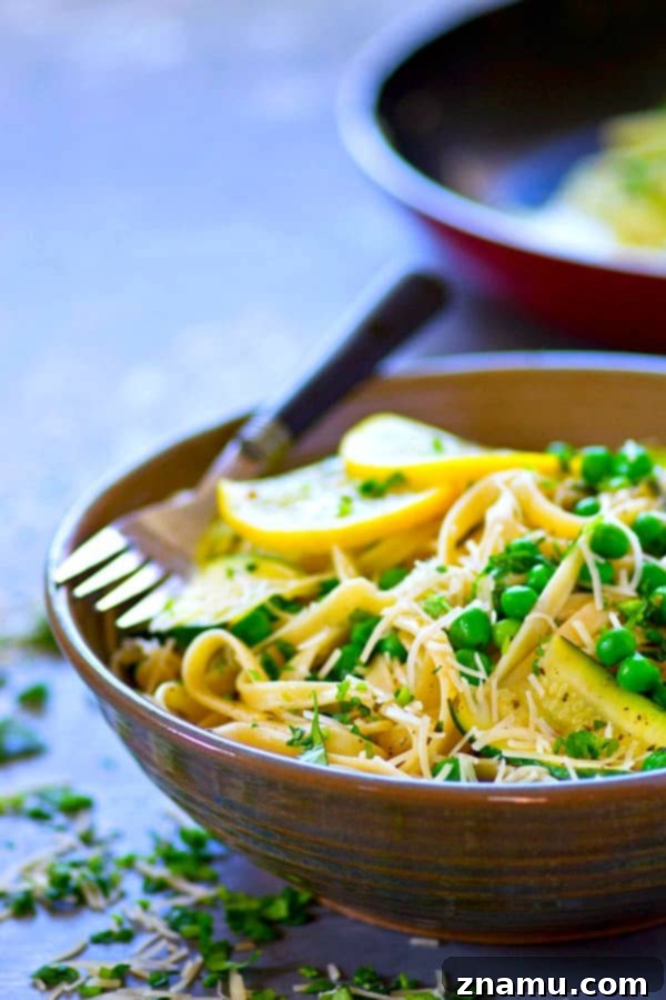 Bright Lemon Parmesan Fettuccine with Zucchini Ribbons and Spring Peas 4 A bowl of Lemon Parmesan Fettuccine garnished with fresh herbs and a sprinkle of cheese.