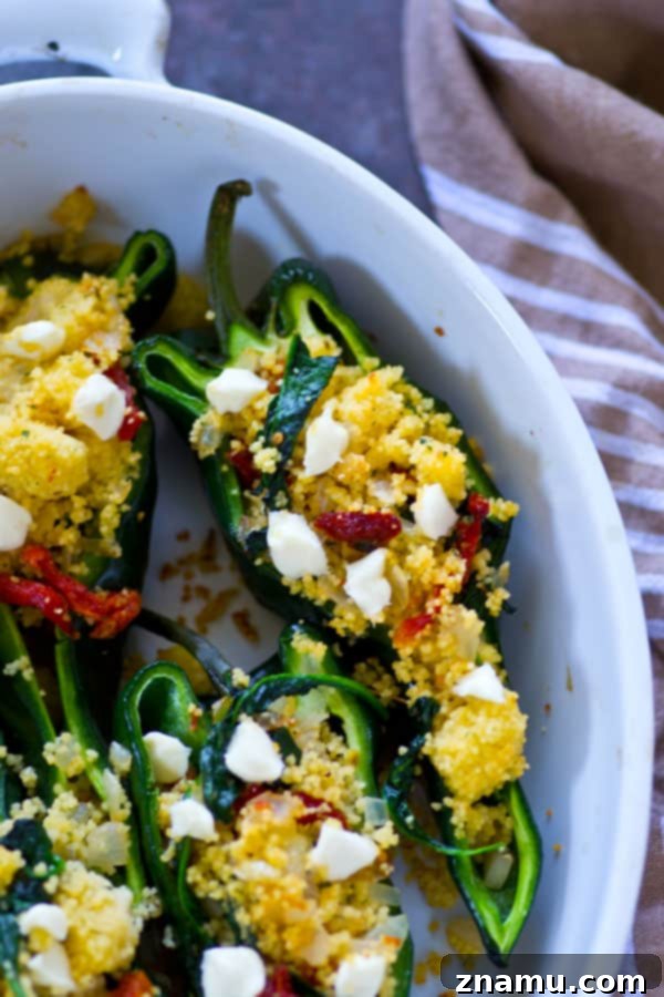 Stuffed poblano peppers topped with goat cheese, ready for baking
