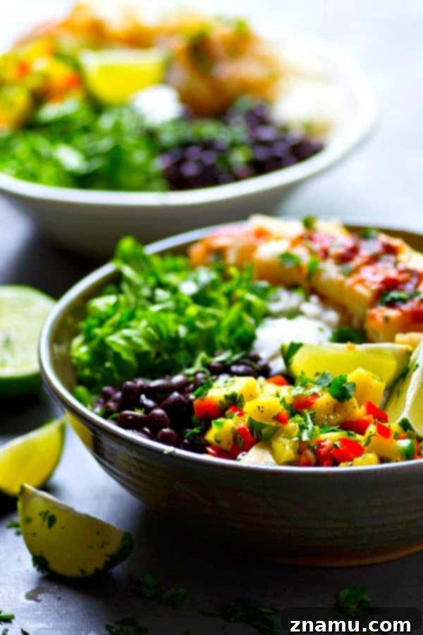 Close-up of a vibrant Chipotle Fish Taco Rice Bowl topped with fresh mango salsa and cilantro.