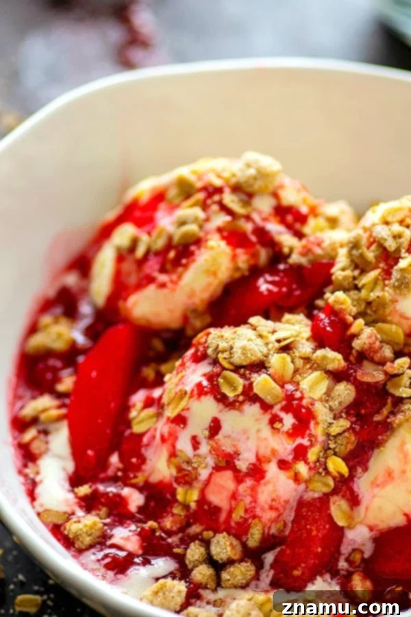 Close-up of Raspberry Peach Melba with rich fruit sauce and crunchy streusel on creamy ice cream.