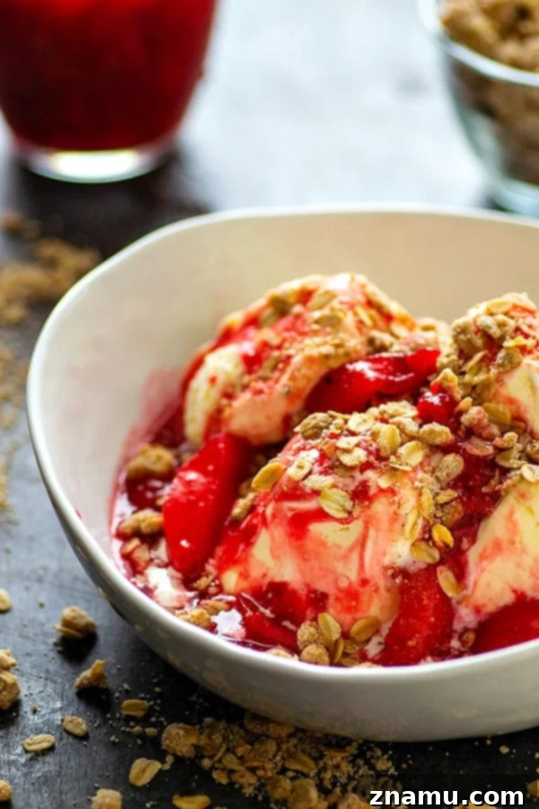 Overhead view of a beautiful Raspberry Peach Melba dessert in a bowl, showcasing layers of ice cream, sauce, and streusel.