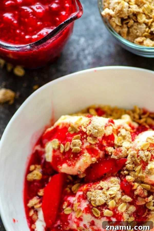 A scoop of vanilla ice cream with raspberry peach sauce and oatmeal streusel, ready to be enjoyed.