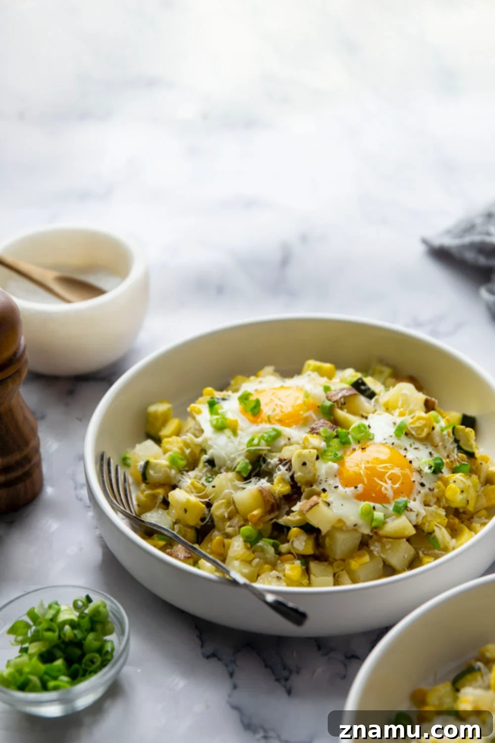 Sunny Summer Squash & Sweet Corn Sheet Pan Hash 4 A close-up of a perfectly cooked sunny-side up egg nestled within the colorful sheet pan hash.