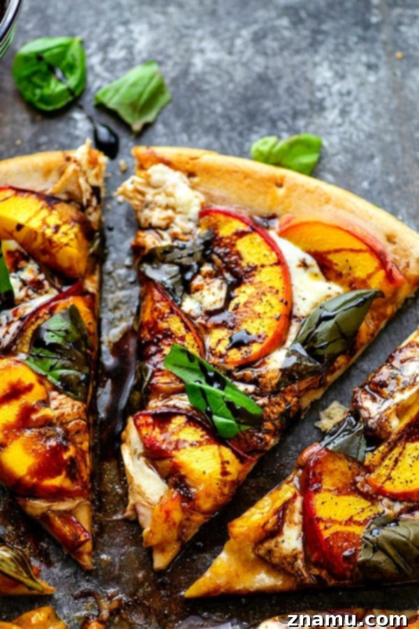 Peachy Balsamic Caprese Pizza 3 An overhead shot of a freshly baked Balsamic Peach Caprese Pizza, showcasing the vibrant colors of peaches, white mozzarella, and green basil against a golden-brown crust.