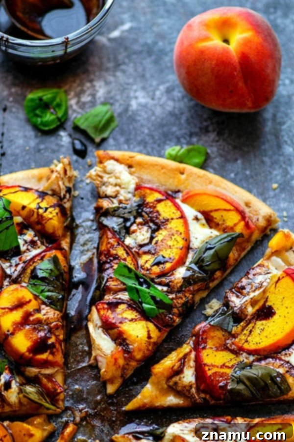 Peachy Balsamic Caprese Pizza 5 A hand holding a slice of Balsamic Peach Caprese Pizza, showing the delicious stretch of melted cheese and the tender peach slices.