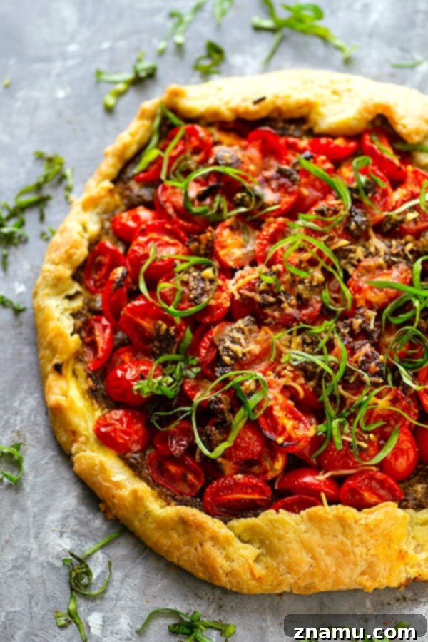 Ricotta Basil Pesto Cherry Tomato Tart 3 Close-up shot of a sliced Ricotta Basil Pesto Cherry Tomato Galette, revealing the creamy ricotta and vibrant pesto underneath the tomatoes.