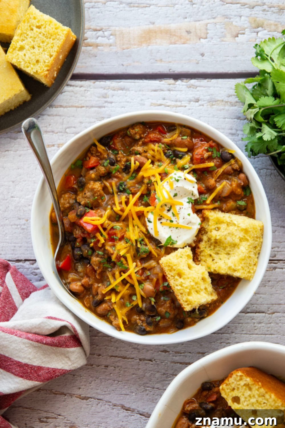 Harvest Gold Pumpkin Chili 2 A steaming bowl of creamy pumpkin chili, generously topped with sour cream, shredded cheese, and fresh cilantro, promising a delightful culinary experience.