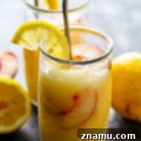 A glass of Frozen Peach Rum Lemonade Slushie, ready to be enjoyed.