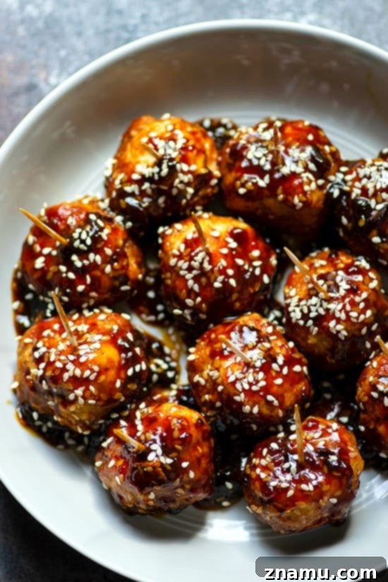Instant Pot Sticky Honey Sesame Chicken Meatballs 3 Instant Pot Honey Sesame Chicken Meatballs - Close-up shot of juicy chicken meatballs coated in a glossy honey sesame sauce, served on a plate with toothpicks, perfect for parties.