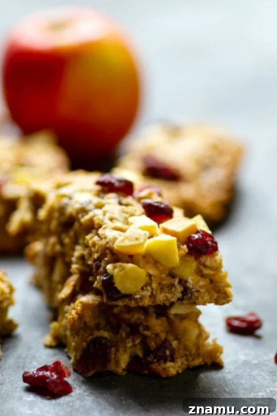 Grab-and-Go Apple Cranberry Oat Bars 4 Stack of freshly baked Cranberry Apple Oatmeal Breakfast Bars, emphasizing their soft texture and how they are packed with fruit. A wholesome and easy breakfast option.