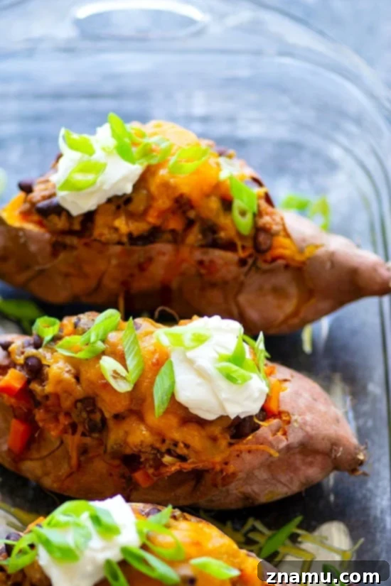 Loaded Turkey Chili Sweet Potato Boats 2 Delicious Turkey Chili Twice-Baked Sweet Potatoes topped with cheese and fresh herbs, presented as a healthier chili alternative.
