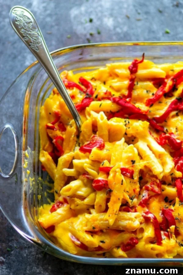 Pumpkin and Roasted Red Pepper Mac & Cheese 2 Baked Pumpkin Roasted Red Pepper Mac 'n' Cheese - A vibrant, cheesy baked pasta dish with a golden crust, featuring elbow macaroni, creamy pumpkin, and bits of red pepper, garnished with fresh parsley.