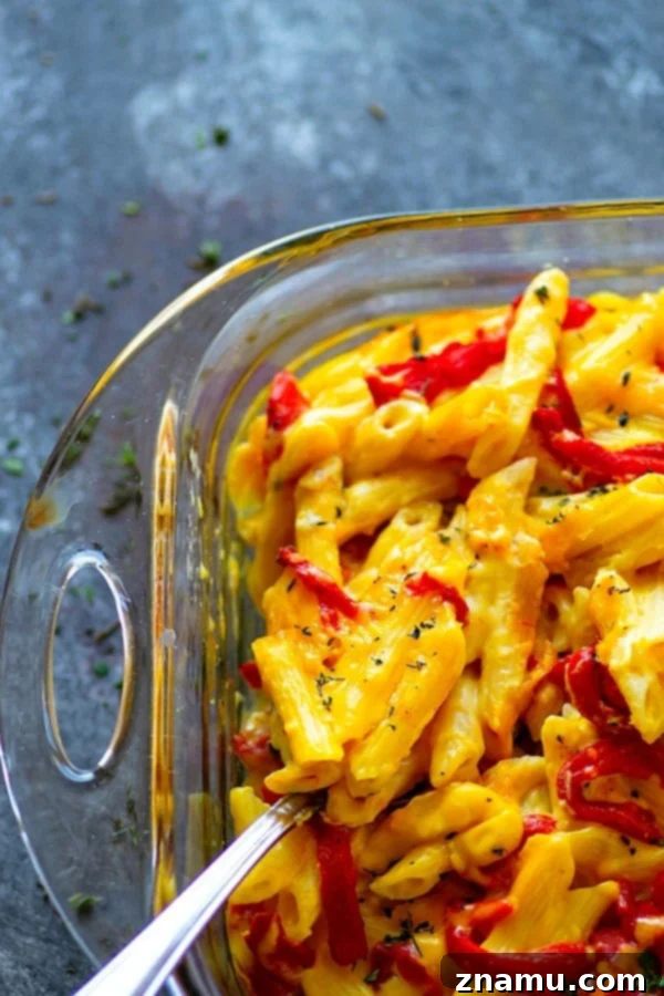 Pumpkin and Roasted Red Pepper Mac & Cheese 3 Baked Pumpkin Roasted Red Pepper Mac 'n' Cheese - Close-up shot of the creamy texture of mac and cheese, showcasing the melted cheese, visible flecks of red pepper, and smooth, orange-hued sauce.