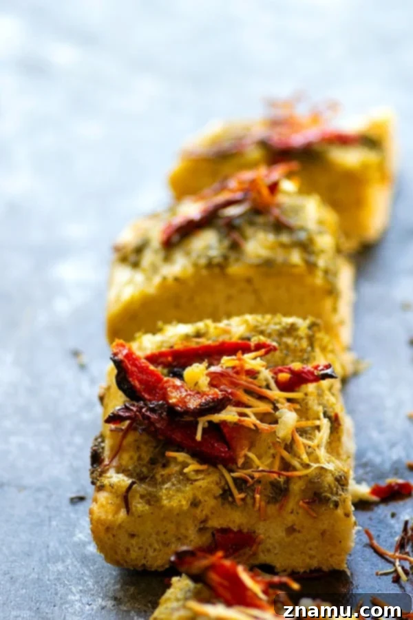 Pesto focaccia square showing a thick, airy crumb and generous toppings