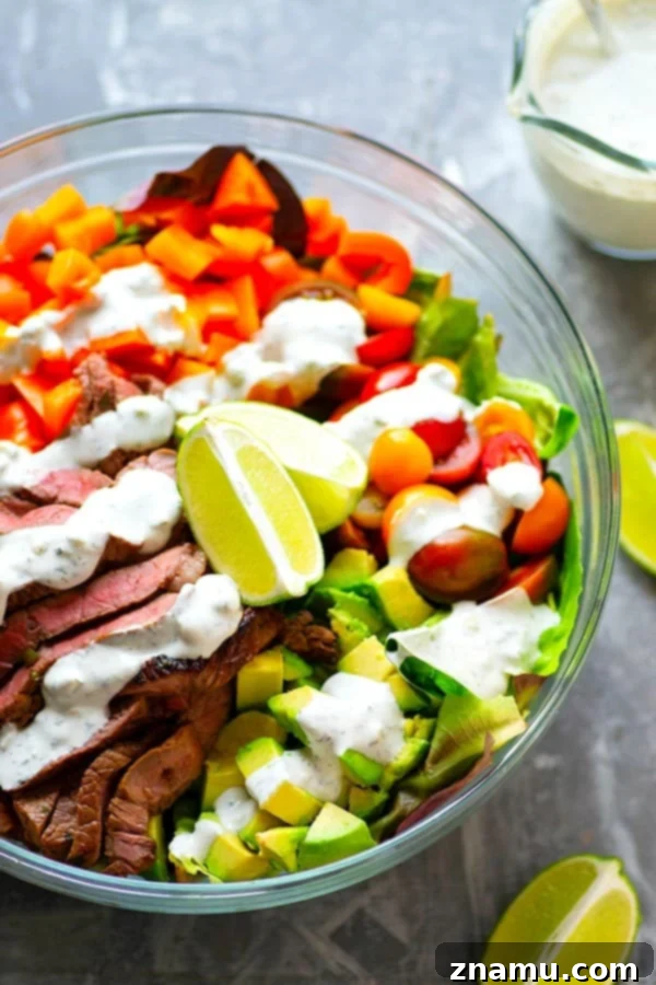 Hearty Carne Asada Bowls with Bold Bleu Cheese 3 A close-up of the fresh ingredients in Carne Asada Steak Salad Bowls, highlighting the vibrant mixed greens, halved cherry tomatoes, and diced sweet peppers, with a hint of creamy bleu cheese dressing.