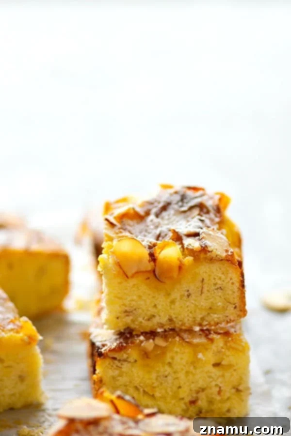 Lemon Curd Almond Butter Cake 2 A gorgeous whole Lemon Curd Almond Butter Cake, freshly baked and dusted with powdered sugar, showcasing its beautiful golden-brown top and scattered almonds.